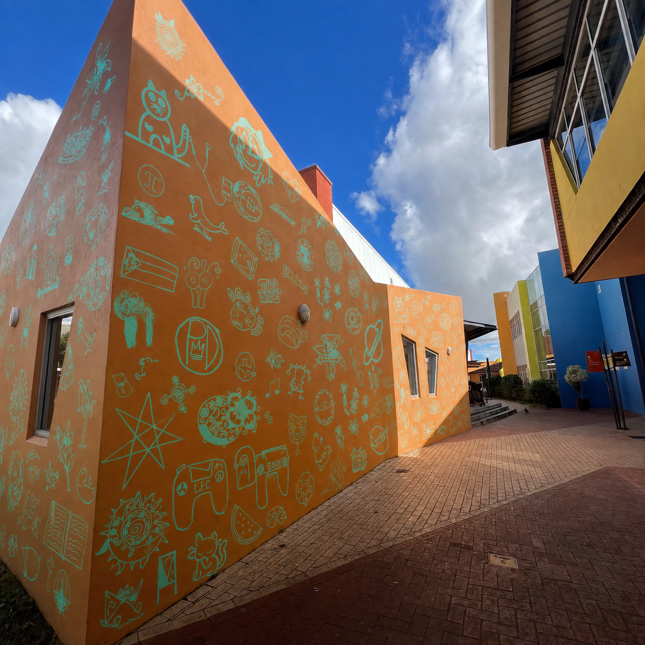 Turquoise student symbols applied across an orange school wall